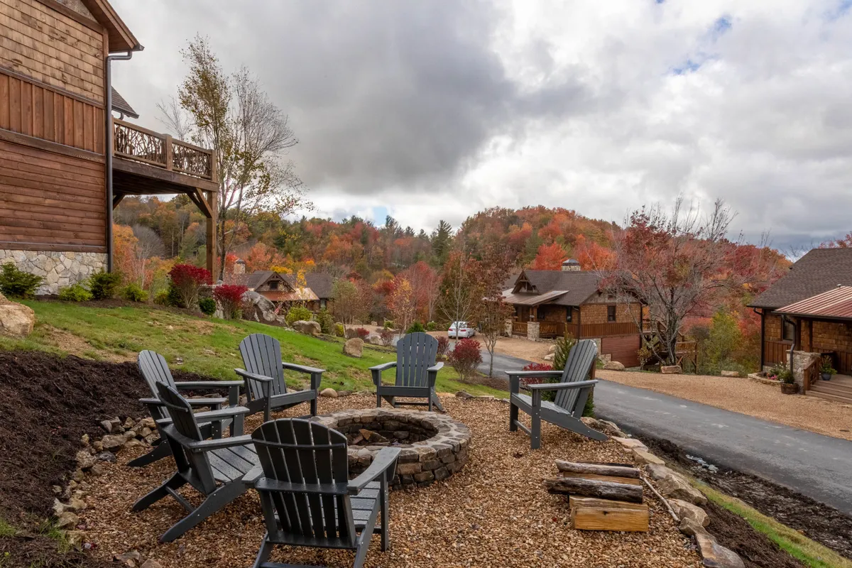 A cozy fire pit setup with Adirondack chairs nestled amidst beautiful foliage. The natural, open setting is ideal for families enjoying sunsets, roasting marshmallows, or simply relaxing together after a day of play.
