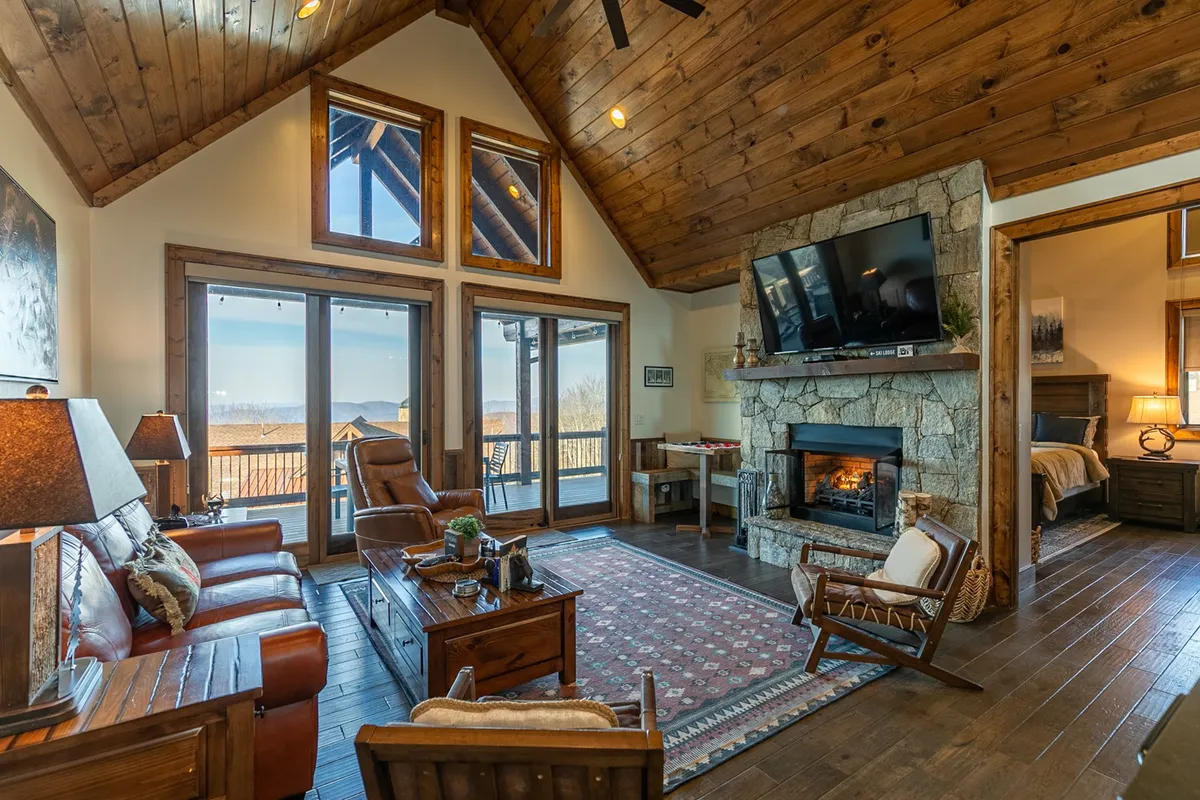 A welcoming living area centered around a stone fireplace, with large windows framing long-range mountain views. Comfortable seating invites guests to relax, whether enjoying a quiet morning coffee or an intimate evening in. The warm, inviting decor underscores the retreat's promise of privacy and relaxation amid breathtaking natural scenery.