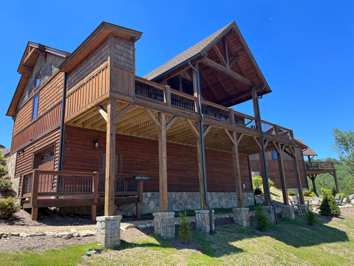 An exterior shot featuring a beautifully crafted wooden and stone structure with a spacious balcony overlooking natural surroundings. The balcony is set up for relaxation and gathering, hinting at activities like stargazing, sunset watching, and enjoying the fresh mountain air—key parts of the resort experience.